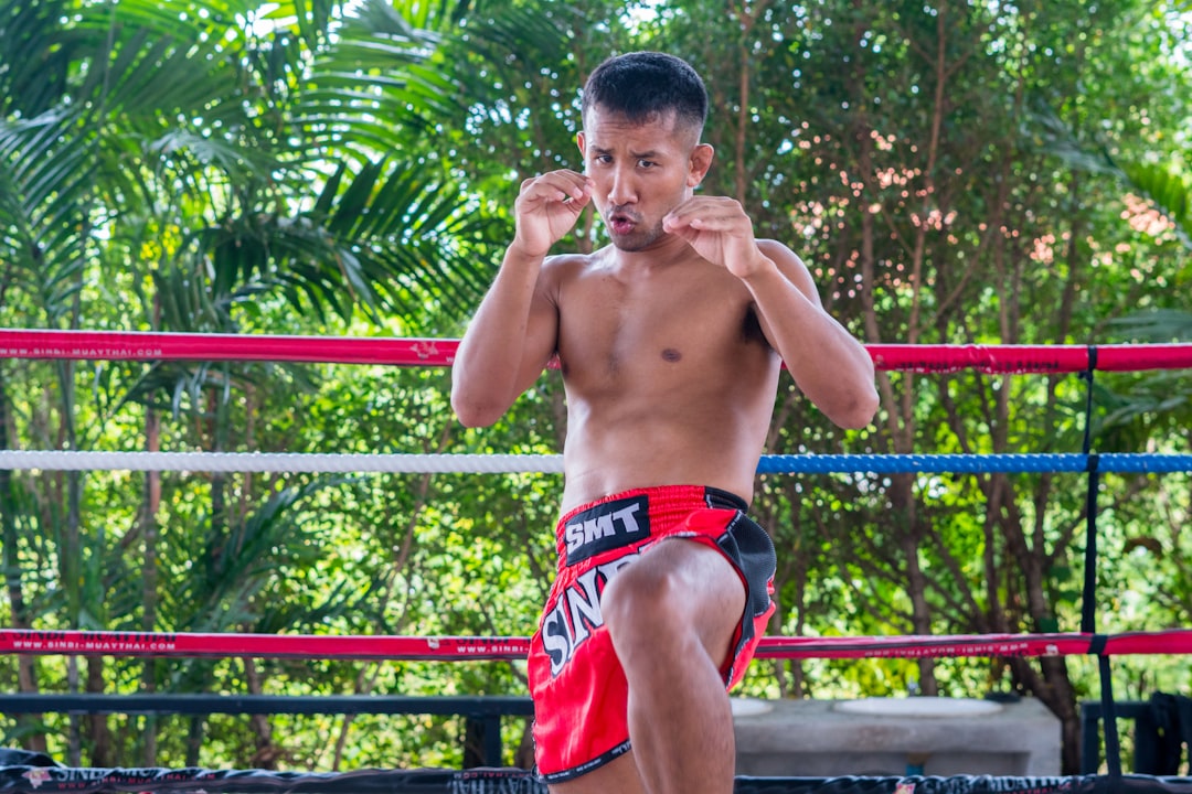 Muay Thai fighter standing in a traditional boxing ring in Thailand, representing the sport's deep history