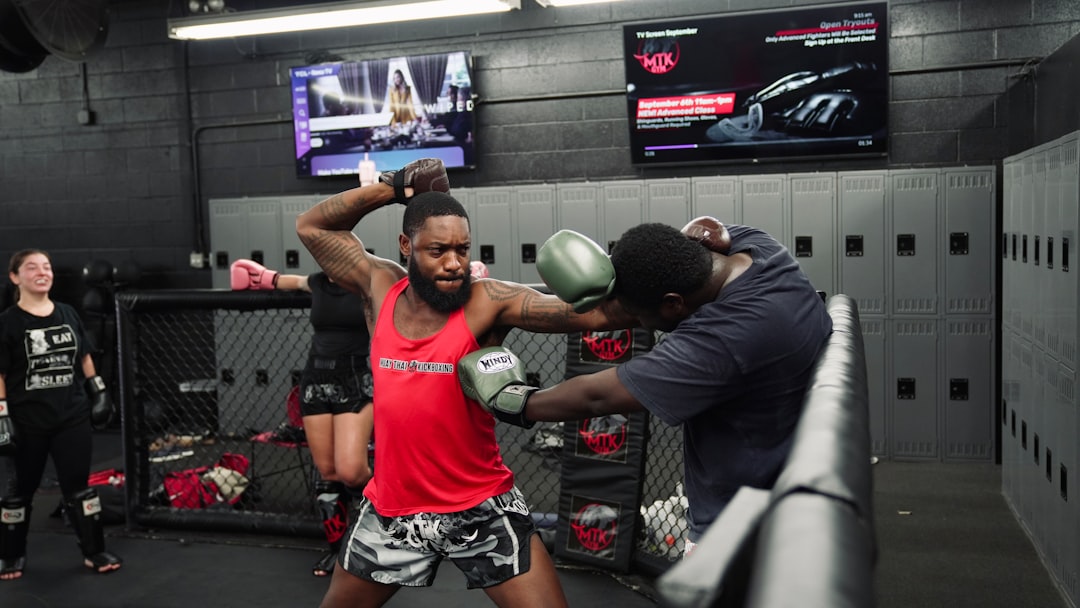 Two men sparring in a boxing ring with trainers watching.